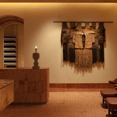 An elegant interior space featuring a stone reception desk, decorative wall hanging, and ambient lighting.