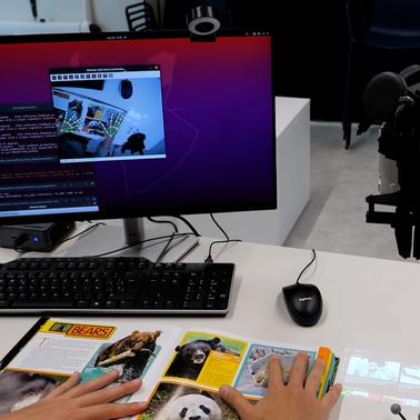 A person interacting with a computer while examining a book about bears.