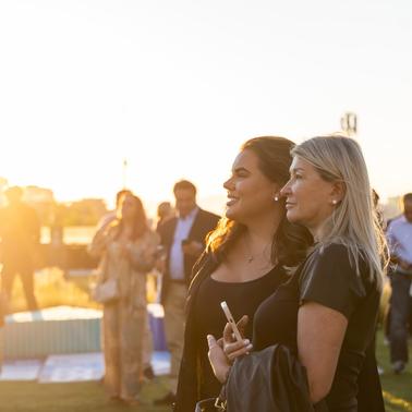 Two women enjoy a sunset during an outdoor gathering.