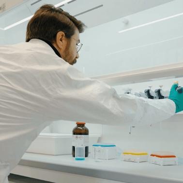 A researcher in a lab coat adjusts equipment in a laboratory setting.