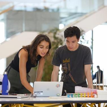 Two young individuals collaborating on a project in a modern workspace.