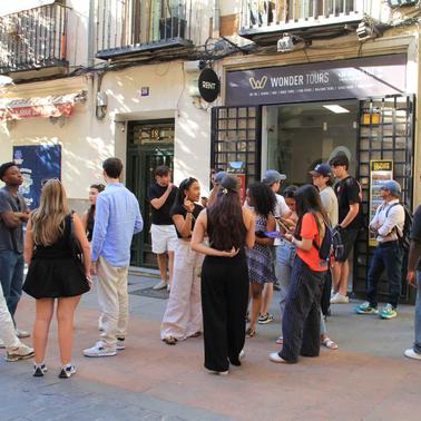 A diverse group of people gathered outside a tour agency in a city.