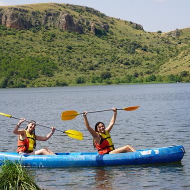 Two people joyfully kayaking on a lake.