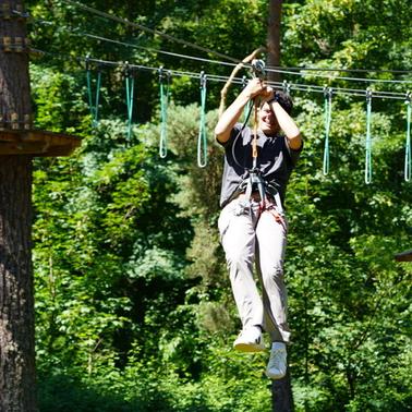 A person is enjoying a zip line adventure in a lush green forest.