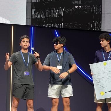 A group of young people presenting on stage with a poster.