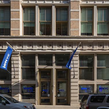A historic building facade with blue flags and large windows in an urban setting.
