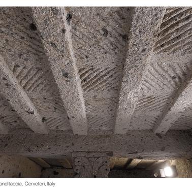 The image shows the intricately patterned ceiling of an ancient funerary site in Cerveteri, Italy.
