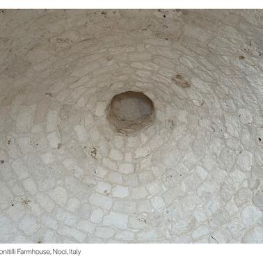 A close-up view of a circular stone floor with a central hole, located in a farmhouse.