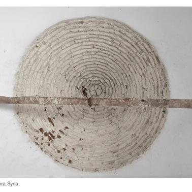 This image shows an agricultural tool made of circular straw intertwined around a wooden stick.