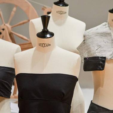 A row of mannequins displaying various dress designs in a workshop setting.