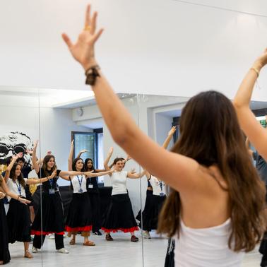 A group of women practicing dance in a studio with mirrors.