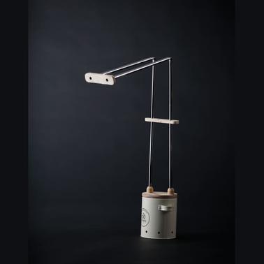 A modern, minimalist desk lamp with a unique mechanical design, featuring a black background.