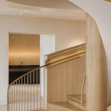 A modern and elegant interior featuring a sweeping staircase with wooden accents and minimalistic decor.