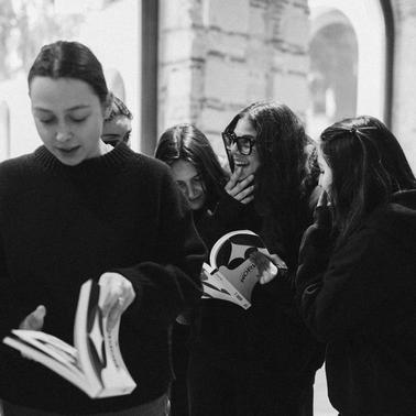 A group of young women are engaging and laughing together while looking at books.