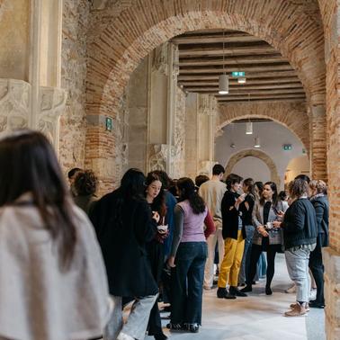 A group of people standing in a line in a corridor with brick arches.