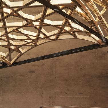 The image showcases a modern architectural ceiling with a unique geometric design made of wood and metal.