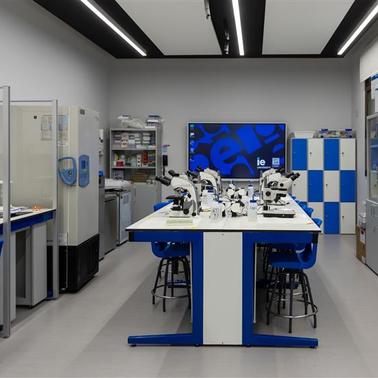 A modern laboratory with microscopes and lab equipment arranged on tables.