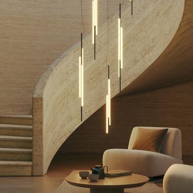 A modern living room with stylish furniture, curved staircase, and elegant hanging lights.