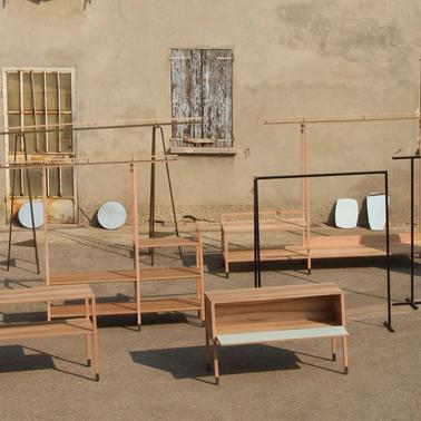 An outdoor display of various wooden furniture pieces including shelves and tables.