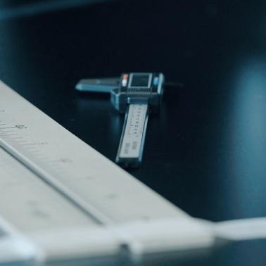 A caliper and a ruler on a dark surface with a small ball.