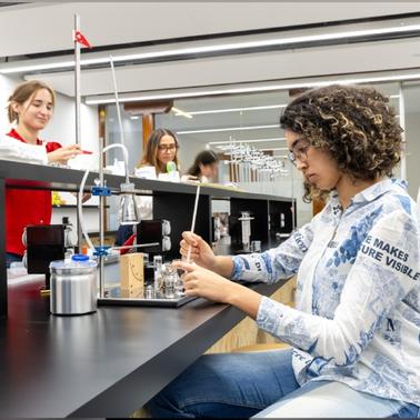 A student is conducting an experiment in a modern laboratory while others observe and participate.