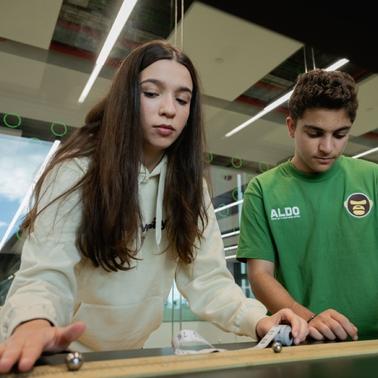 Two young people are concentrating while engaging with a tabletop activity indoors.