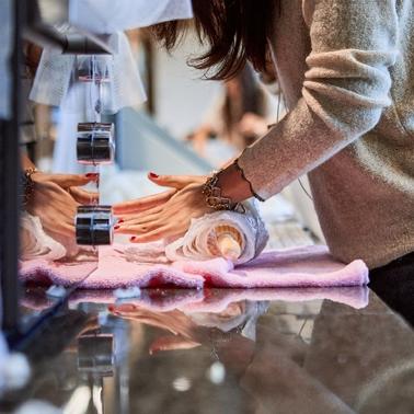A person is placing a rolled item on a counter with a pink cloth.