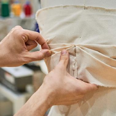 A person adjusting fabric on a dress form.
