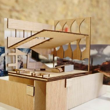 A detailed architectural model made of wood with images in the background.
