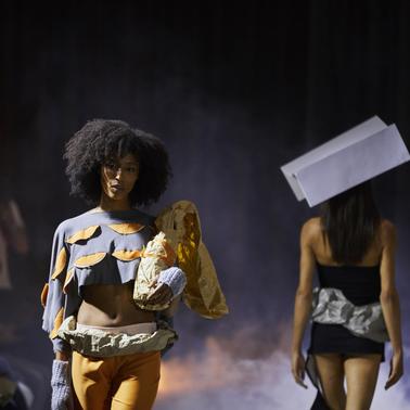 A fashion show featuring models wearing creative outfits on a runway.