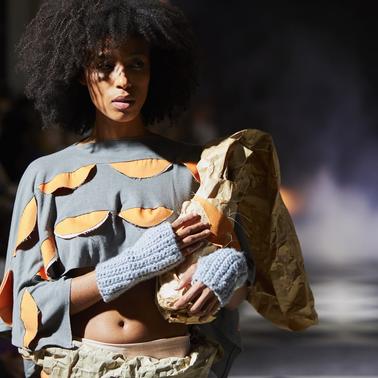 A model walks the runway wearing a unique fashion design with bold textures and colors.