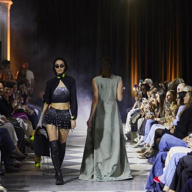 A fashion runway featuring models showcasing trendy outfits amidst an audience.