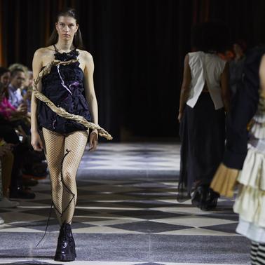 A model walks down the runway wearing a unique fashion outfit during a fashion show.