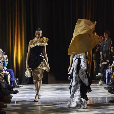 A fashion show featuring models walking down the runway in creative outfits.