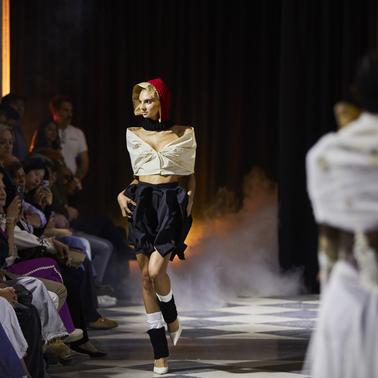 A model walks down the runway wearing a stylish outfit during a fashion show.