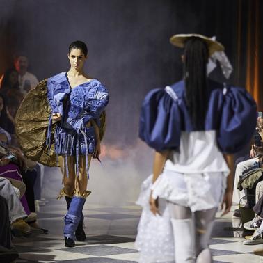 The image showcases a dynamic fashion runway scene featuring models in unique outfits.