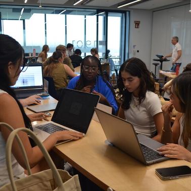 A group of students collaborating on laptops in a classroom setting.