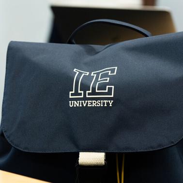 A navy blue backpack featuring the IE University logo.