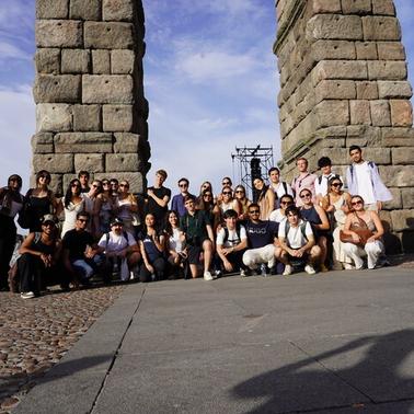A large group of people gathered under ancient stone arches in a historic setting.