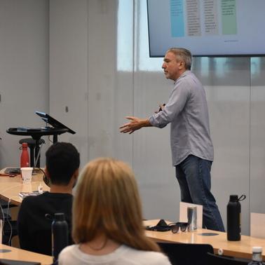 A speaker presenting at a conference with an engaged audience in a modern classroom setting.