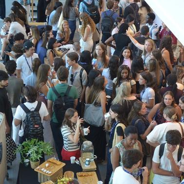 A large group of people socializing in a bustling indoor environment.