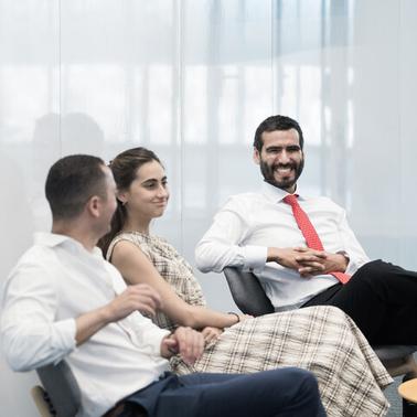 Three people are sitting in a modern office setting, engaged in a conversation.