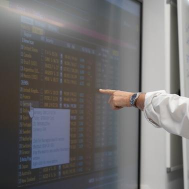 A person pointing at a digital screen displaying data.