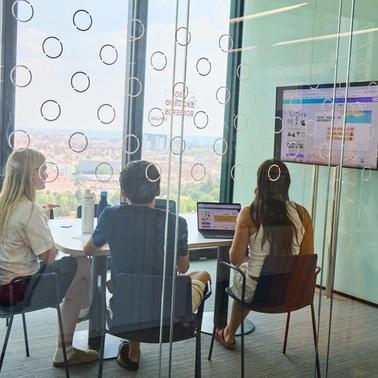 A group of three people collaborating in a modern conference room with a view.
