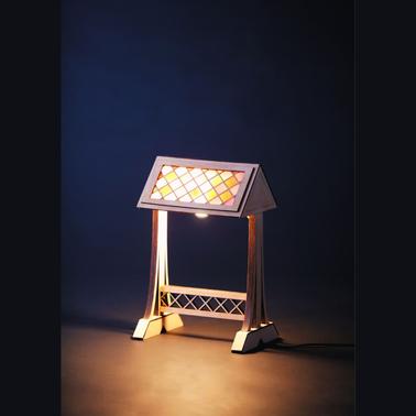 A decorative lamp with a stained glass style shade on a wooden stand, illuminated against a dark background.