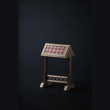 An elegant wooden stand displaying an ornate, patterned surface against a dark background.