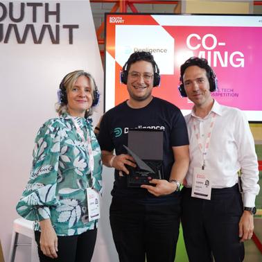 Three people posing together at a tech event, with one of them holding an award.