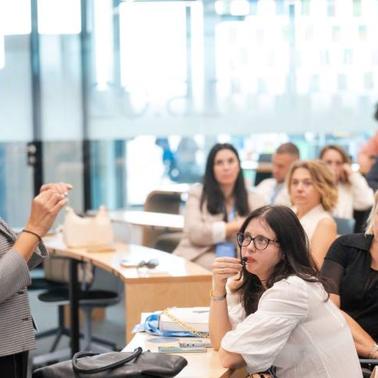 A woman is giving a presentation to a group of attentive listeners in a modern office environment.