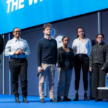 A group of young professionals standing together on stage during a presentation.