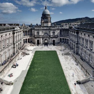 A view of a grand classical building with an open courtyard, under a clear sky.